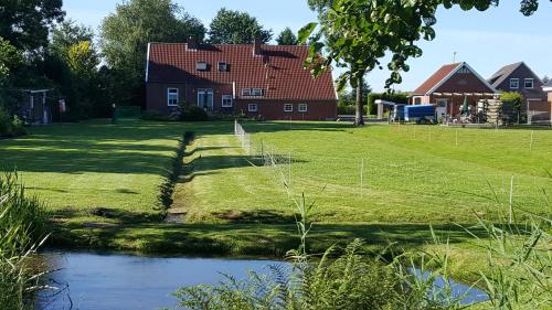 a house with a pond in front of a yard at Ferienwohnung am Sandwater 