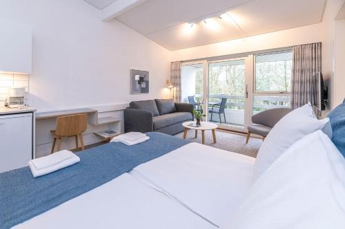 a bedroom with a large bed and a living room at Strandhotel Balka Søbad in Neksø