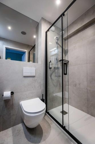 a bathroom with a toilet and a glass shower at Apartamenty Wolności 6 self check-in 24h in Poznań