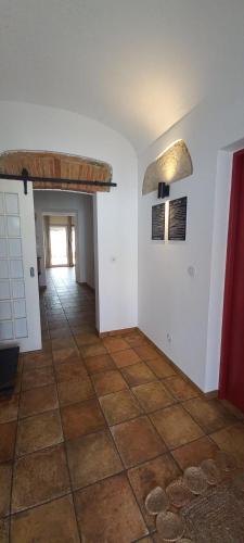a room with a tile floor and white walls and a hallway at Paredes com Memória in Vila Ruiva