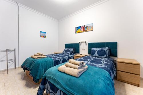 Dos camas en una habitación con edredones azules. en 234 Parque playa La cala, en La Cala de Mijas