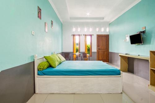 a bedroom with a bed with a blue wall at Joglo Ndalem Sabine Syariah in Piyungan