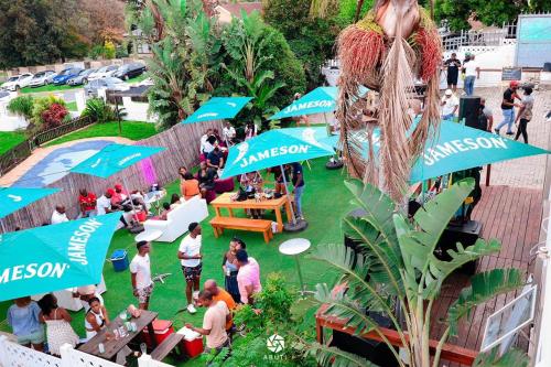 un grupo de personas sentadas bajo sombrillas en un evento en Comfort Home Guest House, en East London
