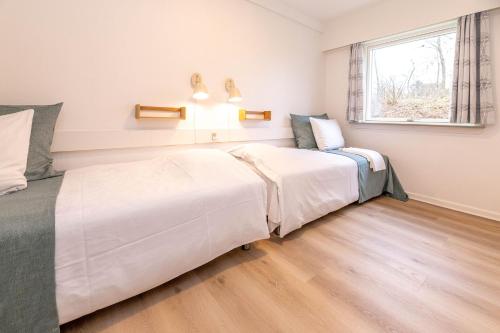 two beds in a room with a window at Strandhotel Balka Søbad in Neksø