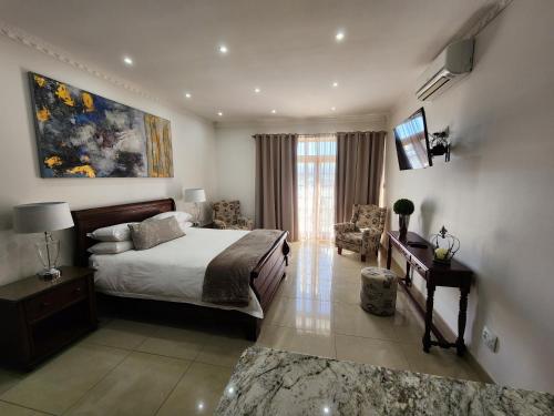 a bedroom with a bed and a couch and a television at Villa Marche in Van Riebeekhoogte