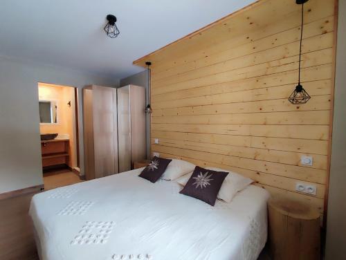 a bedroom with a white bed with a wooden wall at Luxueux appartement T4 skis aux pieds à Tignes le Lac in Tignes