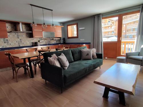 ein Wohnzimmer mit einem grünen Sofa und einem Tisch in der Unterkunft Luxueux appartement T4 skis aux pieds à Tignes le Lac in Tignes