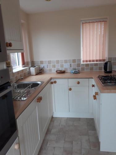 a kitchen with white cabinets and a sink at Garden Cottage in Stone