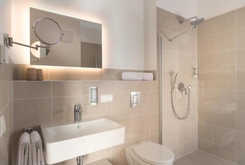 a bathroom with a sink and a toilet and a mirror at Atrium Apart Hotel Brühl in Brühl