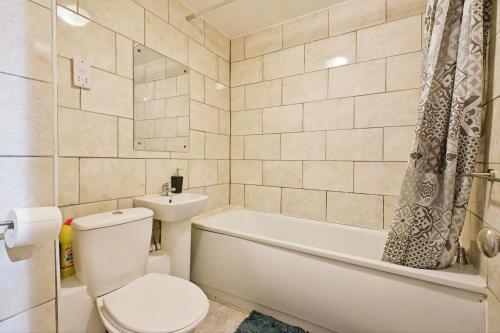a bathroom with a toilet and a tub and a sink at Manor Place Apartment Thamesmead in Thamesmead