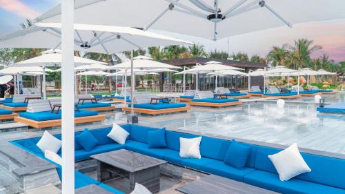 a pool with blue couches and white umbrellas at Da Nang - Mikazuki Japanese Resorts & Spa in Da Nang