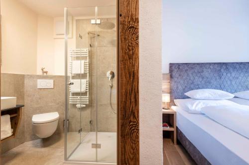 a bathroom with a shower and a bed and a toilet at NATURPARKGUT - Apartment HOLZGAU1758 in Holzgau