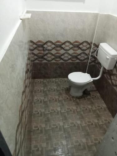een badkamer met een toilet op een bakstenen vloer bij Trishul holidays in Alāndurai