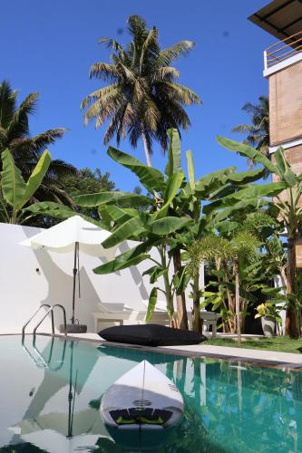 a pool with a chair and an umbrella and palm trees at OASIA - Boutique Surf House (ADULTS ONLY) in Weligama