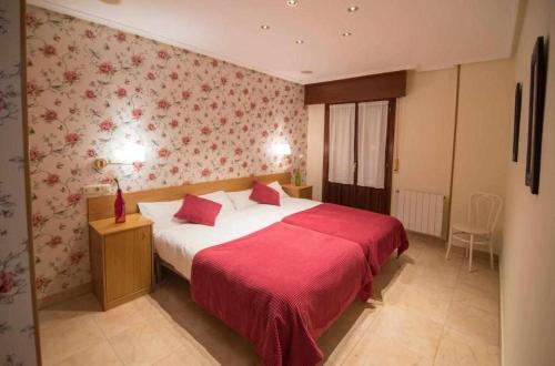 1 dormitorio con 1 cama grande con manta roja en Apartamentos Mugarri, en Poveña