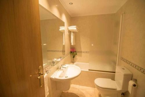 a bathroom with a white toilet and a sink at Apartamentos Mugarri in Poveña