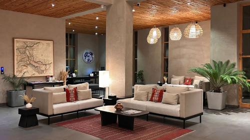 a lobby with two white couches and a table and potted plants at Chospa Hotel, Leh in Leh