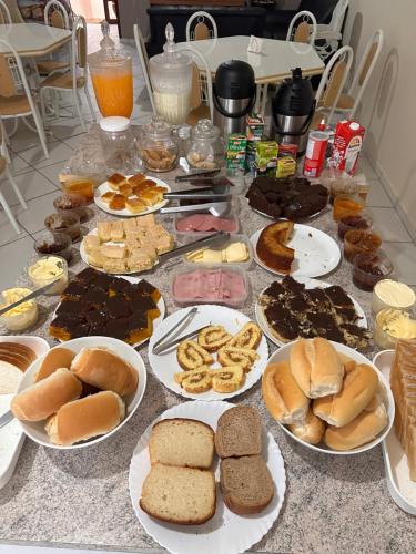 uma mesa com pratos de pastelaria e outros alimentos em HOTEL Rafael em Bom Retiro