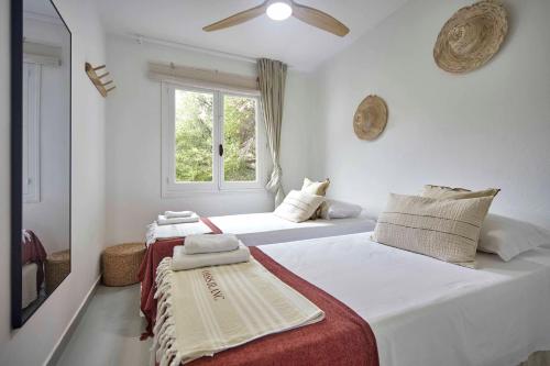 two beds in a white room with a window at OasisBlanc Binibeca in Binibeca