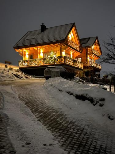 a large wooden house with lights in the snow at Houten Vakantiewoning "ReisnaarPolen" inclusief royaal ontbijt, sauna en gids in Czarna Góra
