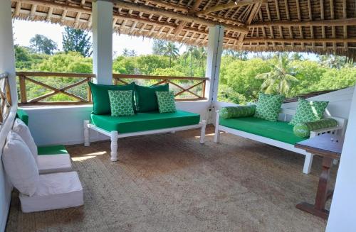 a porch with green chairs and a table at Watamu Beach Cottages B&B in Watamu