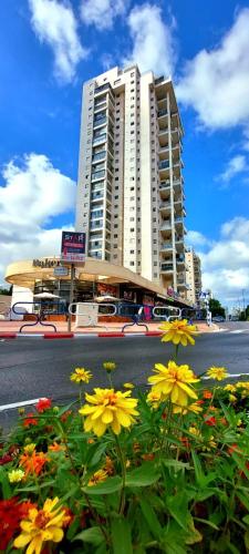 アシュドッドにあるapartments with separate kitchen by the seaの通りの前に花の咲く高い建物
