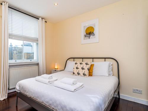 1 dormitorio con 1 cama con 2 toallas en Pass the Keys West End Apartment near Tottenham Court Road, en Londres