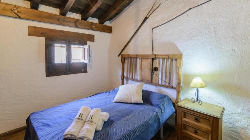 een slaapkamer met een bed met twee paar schoenen erop bij Combinación Serval y Pedrizas Montefrío by Ruralidays in Montefrío