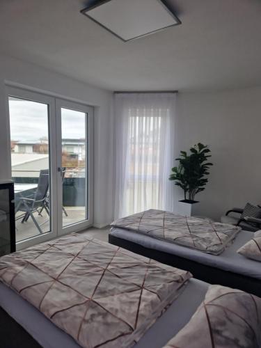 a bedroom with two beds and a window with a patio at Ferienwohnung Alona in Engelsbrand