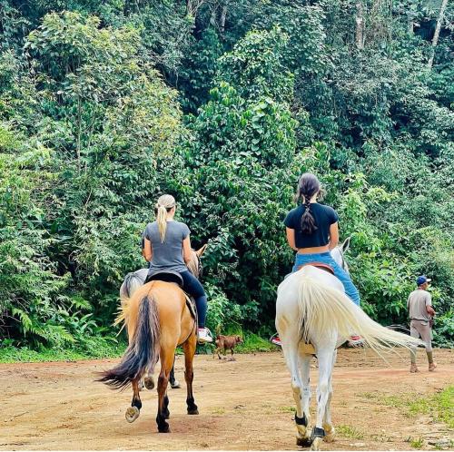 dos mujeres montando a caballo en un camino de tierra en Pousada Jupter, en Teresópolis