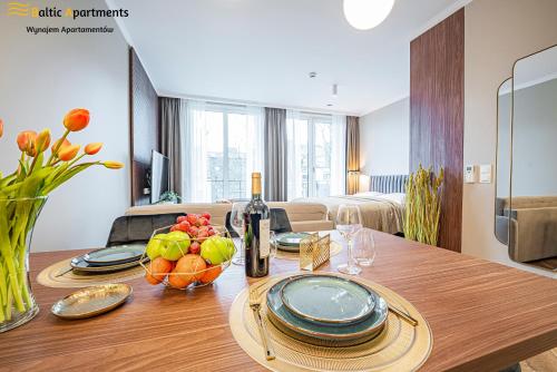 a dining room table with a bottle of wine and fruit at Baltic Apartments - Seaside Garden Apartments & Wellness in Świnoujście