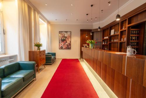 a red carpet in a waiting room with a red rug at Hotel Carlton Munich in Munich