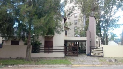 un edificio blanco con un árbol delante en Complejo Arena Malva en San Bernardo