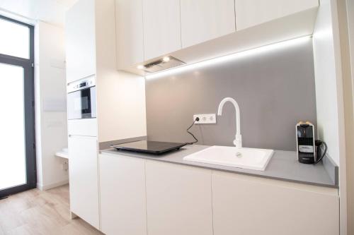 una cocina con armarios blancos y fregadero en MARITIM 1 by Concept, en Valencia