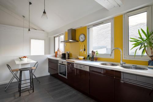 een keuken met gele en witte muren en houten kasten bij Atypical Luxury House near Paris in Boulogne-Billancourt