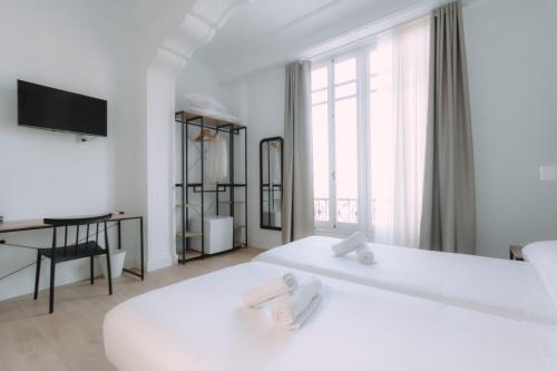 a white bedroom with two beds and a desk at Clink Rooms & Flats in Valencia