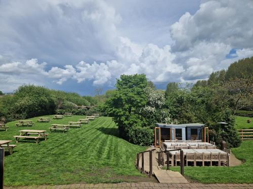 a field with tables and picnic tables in the grass at The Star in West Leake