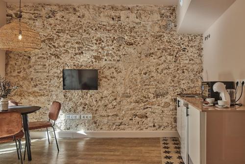 a kitchen with a stone wall with a tv on it at VG - Villa de Andas suites in Cádiz