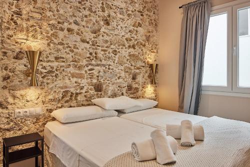a bedroom with two beds and a brick wall at VG - Villa de Andas suites in Cádiz