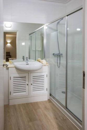 a white bathroom with a sink and a shower at Vitor s Plaza Mariosilvat in Portimão