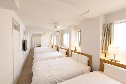 大阪市にあるHaginochaya apartmentの白いベッドが並ぶ部屋