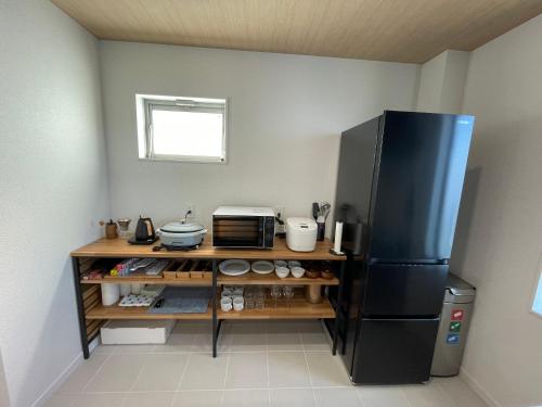 a kitchen with a black refrigerator and a counter at さんぽ 1日1組限定のプライベートヴィラ in Hayama