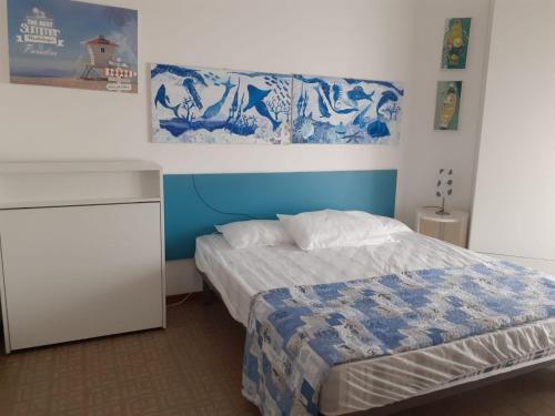 リド・ディ・イエゾロにあるRESIDENCE APOLLO - WALTERIGATO Apartments SOLO PER FAMIGLIEのベッドルーム1室(ベッド1台付)が備わります。壁には絵画が飾られています。