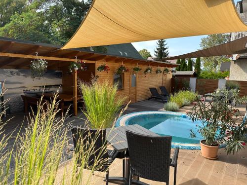 eine Terrasse mit einem Tisch, Stühlen und einem Pool in der Unterkunft VillaBoglár in Balatonboglár