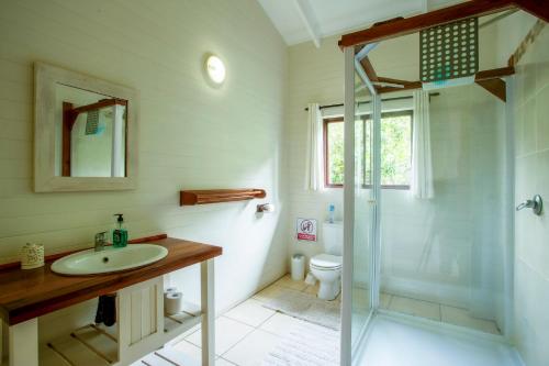 ein Bad mit einer Glasdusche und einem Waschbecken in der Unterkunft Mar Azul 1B in Ponta Malangane