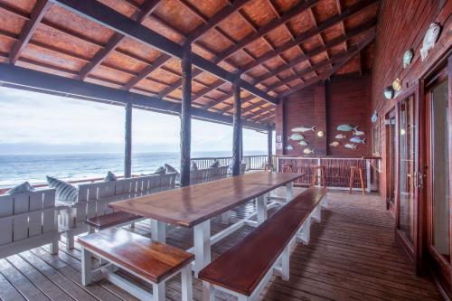 a dining room with a table and benches and the ocean at Mar Azul 1B in Ponta Malongane