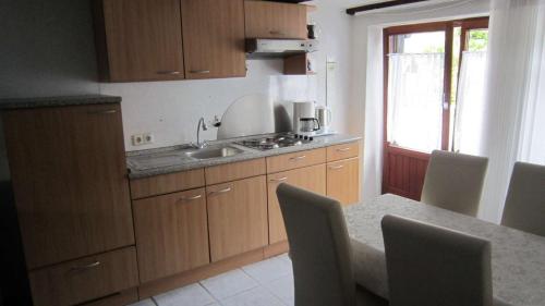 a kitchen with wooden cabinets and a table with chairs at Haus Biggi - Ferienwohnung Hochgrat in Weiler-Simmerberg