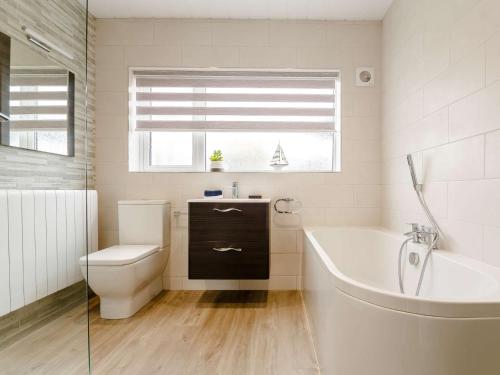 een badkamer met een bad, een toilet en een wastafel bij 2 Bed in Moelfre 75013 in Moelfre