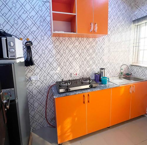 an orange kitchen with a sink and a stove at Signature Residence in Calabar