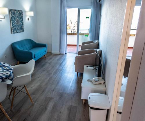 una sala de espera con un sofá azul y sillas en Apartamentos Buensol, en Torremolinos